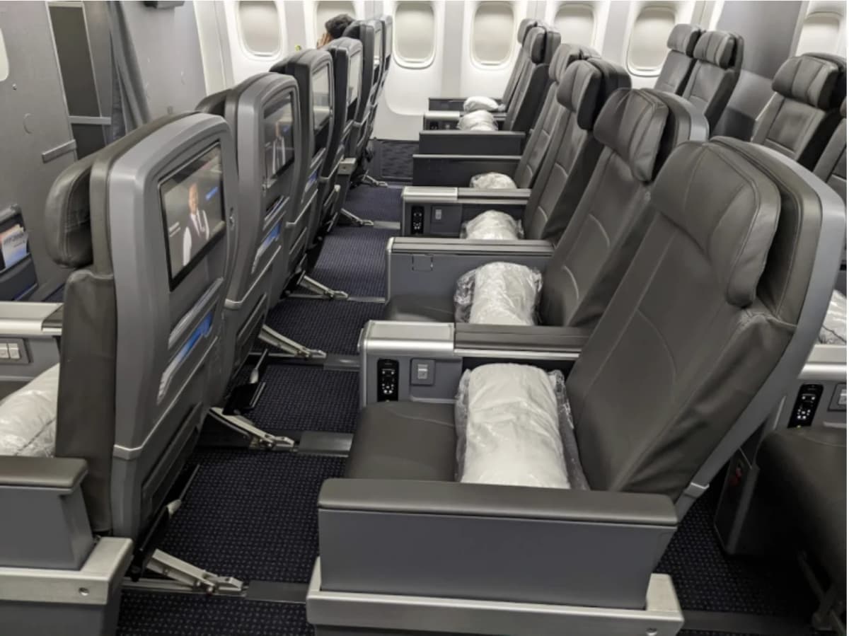 American Airlines Premium Economy / 777-300ER cabin — dual-tone gray leather seats with IFE-equipped seatback, the actual cabin most AAdvantage Web Specials redemptions land in